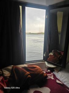 een slaapkamer met een raam met uitzicht op het water bij The grand in Nag` el-Ramla