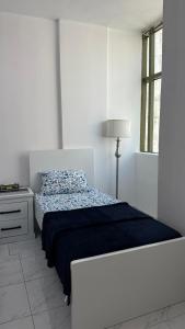 沙迦Bed space in Luxury hostel - سرير مفردفي شقة فندقية的白色卧室配有床和灯