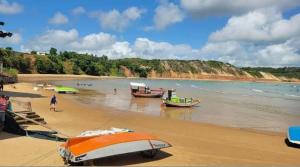 two boats on a beach with people in the water at Pousada Castelo do Gaúcho in Baía Formosa
