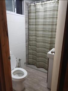 ein Badezimmer mit Toilette und Duschvorhang in der Unterkunft Casa en Cuchilla Alta Biarritz in Cuchilla Alta + 3 Fotos