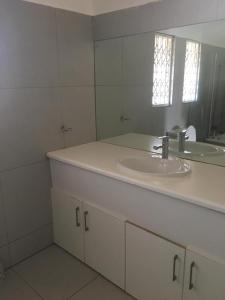 Primestay Homestead في غابورون: حمام أبيض مع حوض ومرآة