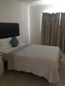 Primestay Homestead في غابورون: غرفة نوم بها سرير بملاءات بيضاء ونافذة