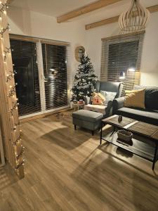 - un salon avec un arbre de Noël et un canapé dans l'établissement SierPlejs Hill - domki przy szlaku w Górach Sowich, à Sierpnica