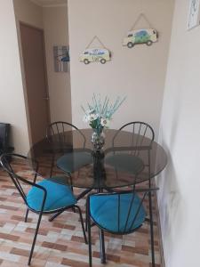 a glass table with chairs and a vase with flowers at Departamento en el Tabo in El Tabo