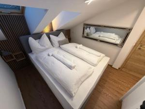a white bed with white pillows and a mirror at Alpinoase City Centre Zell am See in Zell am See