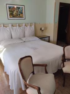 a bedroom with a large white bed with two chairs at Alf e Ann B&B in Tivoli Terme
