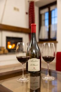 twee wijnglazen naast een fles wijn bij Maison Plan de Dieu in Saint-Pierre