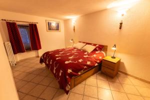 een slaapkamer met een bed met een rood dekbed bij Maison Plan de Dieu in Saint-Pierre