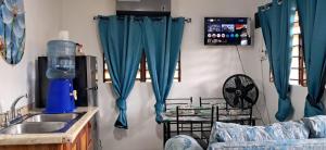 cocina con cortinas azules y fregadero en Delva's Villa - Cozy Home near Airport, en Ladyville