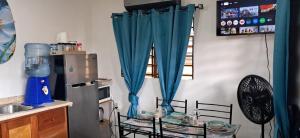 a kitchen with blue curtains and a refrigerator at Delva's Villa - Cozy Home near Airport in Ladyville