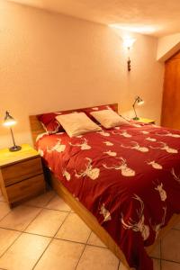 een slaapkamer met een bed met een rood dekbed bij Maison Plan de Dieu in Saint-Pierre