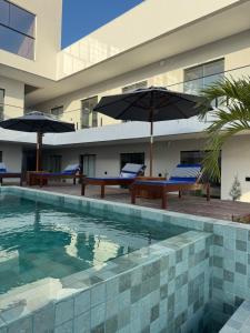 a swimming pool with two benches and umbrellas at Vila Eco Barra AP 209 in Barra Grande