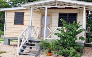 Una pequeña casa con porche y escalera. en Delva's Villa - Cozy Home near Airport, en Ladyville