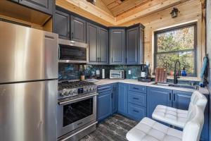 una cucina con armadi blu e frigorifero in acciaio inossidabile di Kings River Micro Cabin a Eureka Springs