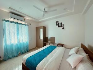THS Suites - Luxurious 2 BHK AC apartments with Tirumala Views - Near Marriott, Taj and ITC 5 star hotels - Walkable to PS4, A2B, Orion, Starbucks cafes - Close to Thiruchanur and Alipiri flyover في تيروباتي: غرفة نوم بسرير كبير مع ستائر زرقاء
