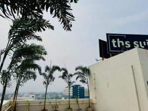 THS Suites - Luxurious 2 BHK AC apartments with Tirumala Views - Near Marriott, Taj and ITC 5 star hotels - Walkable to PS4, A2B, Orion, Starbucks cafes - Close to Thiruchanur and Alipiri flyover في تيروباتي: علامة على رأس مبنى به أشجار النخيل