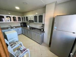 a kitchen with a stainless steel refrigerator and white cabinets at 2 BR apartment - City Center Residency - Panoramic City Views - 3 Min Train Access by ZenStay in Fès +34 photos