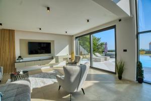 een woonkamer met een televisie en een bank en stoelen bij Villa Bella in Bale