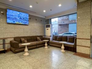 a waiting room with a couch and a tv at فندق مهوى الفؤاد - المعابدة in An Naqāʼ