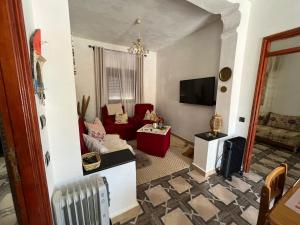 a living room with a red couch and a tv at Le P’tit Coin D’Akchour in Akchour