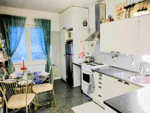 a kitchen with white cabinets and a table with chairs at Romanttinen Retrokaksio in Oulu