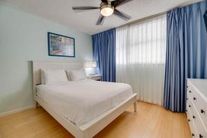 ein Schlafzimmer mit einem weißen Bett und blauen Vorhängen in der Unterkunft The Cayo Coco | Key West Condo with Pool Hot Tub & Balcony Views in Key West + 19 Fotos