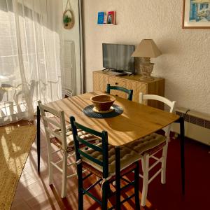 a dining room table with chairs and a bowl on it at Idyllique ! Terrasse vue jardin et montagne, parking, local à vélos, à 2 pas de la plage et piscine de mai à septembre ! in Argelès-sur-Mer