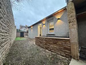 een huis met een bakstenen muur en een raam bij Maison le petit coin secret in Châtillon-sur-Seine