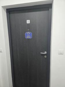 a black door with a blue sign on it at Apartman Mir in Temerin