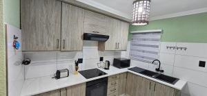 Mountain Ridge Lux Stay في روستنبرج: مطبخ بجدران بيضاء وأخضر وخزانات خشبية