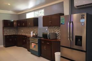 a kitchen with wooden cabinets and a stainless steel refrigerator at Costabay in El Zapote