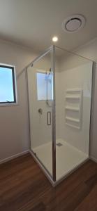 a glass shower stall in a room with a window at Bumble Bee Cottage in Kerikeri