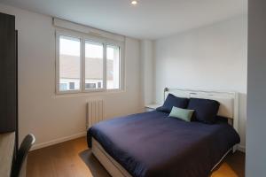 a bedroom with a bed with blue pillows and a window at Coliving Henri Barbusse - salle de sport - chambres avec SDB privative in Le Mans +28 photos