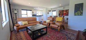 a living room with a couch and chairs and a table at Bumble Bee Cottage in Kerikeri