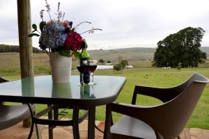 a table with two glasses of wine and a vase with flowers at Uitvlugt Ponds in Dullstroom +28 photos