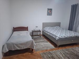a bedroom with two twin beds and a table at Paviljoni apartman in Tošin Bunar