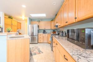 a large kitchen with wooden cabinets and stainless steel appliances at Charming beach home with Ocean & Mt. Baker View in Camano +36 photos