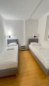 two beds in a room with wooden floors and white walls at Apartamenty Dąbrówka Cieplice Zdrój 1,15 in Jelenia Góra
