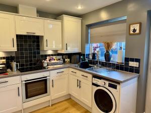 a kitchen with white cabinets and a washer and dryer at Willow Cottage in North Muskham