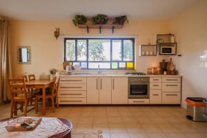 a kitchen with white cabinets and a table and a window at אירוח בעמק in Yesod Hamaala