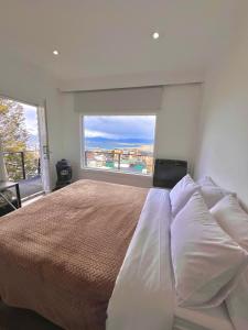Casa Mirador Austral La familia entera en un solo lugar con una increíble vista y tranquilidad في أوشوايا: غرفة نوم بسرير كبير مع نافذة كبيرة
