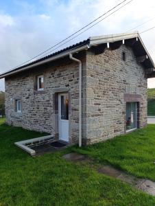a stone house with a white door and grass at Le Grand Meix - La Petite Grange in Escles