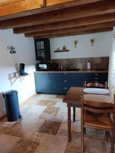 a kitchen with a wooden table and blue cabinets at Le Grand Meix - La Petite Grange in Escles +3 photos