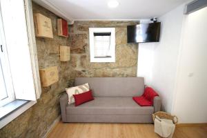 - un canapé dans une chambre dotée d'un mur en pierre dans l'établissement Lady Vine by Lady Collection, à Porto