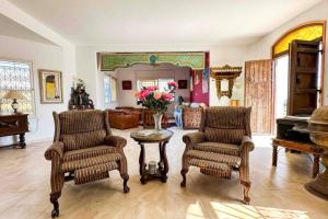 Dar RetbaにあるDar Kmar A sweet getaway in the hills of Hammametのリビングルーム(椅子2脚、花のテーブル付)