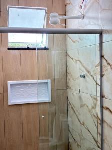 a shower with a glass door and a window at Pousada sussego in Prado