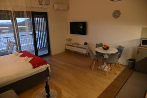 a bedroom with a bed and a table and a kitchen at Apartman Perfect in Trebinje