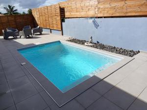 a swimming pool on a patio with chairs and a building at Villa Lilisse in Le Moule