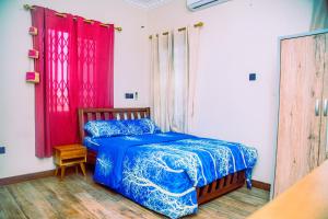 Aubri Homes في آكرا: غرفة نوم بسرير ازرق وستائر حمراء