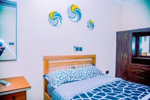 Aubri Homes في آكرا: غرفة نوم بها سرير وثلاث موجات على الحائط